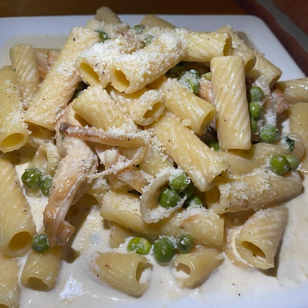 Rigatoni pasta with creamy white sauce, green peas, chicken, and grated Parmesan cheese.