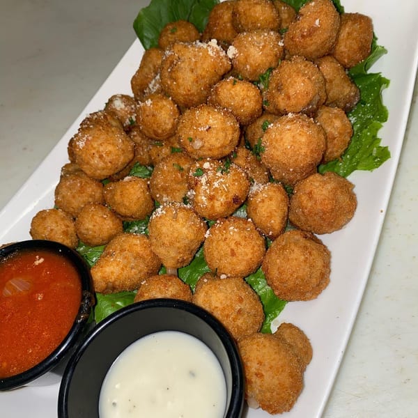 A platter of golden-brown fried mushrooms with parmesan, parsley, and dipping sauces.